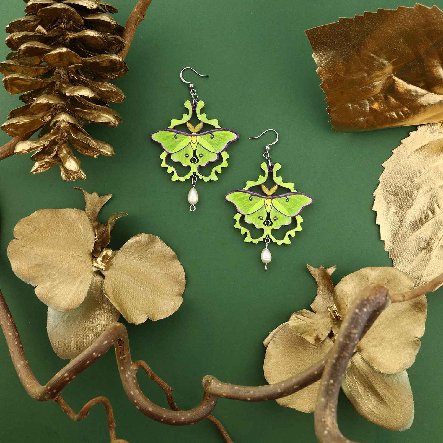 Pikku Luna moth vanerikorvakorut - roikkuvat korvakorut tummanvihreällä taustalla